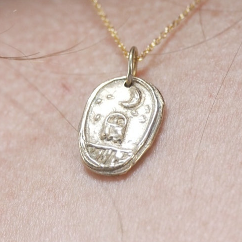 Gold necklace with a pendant on a person's neck