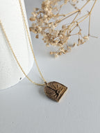 Gold necklace with a heart-shaped pendant on a light gray background