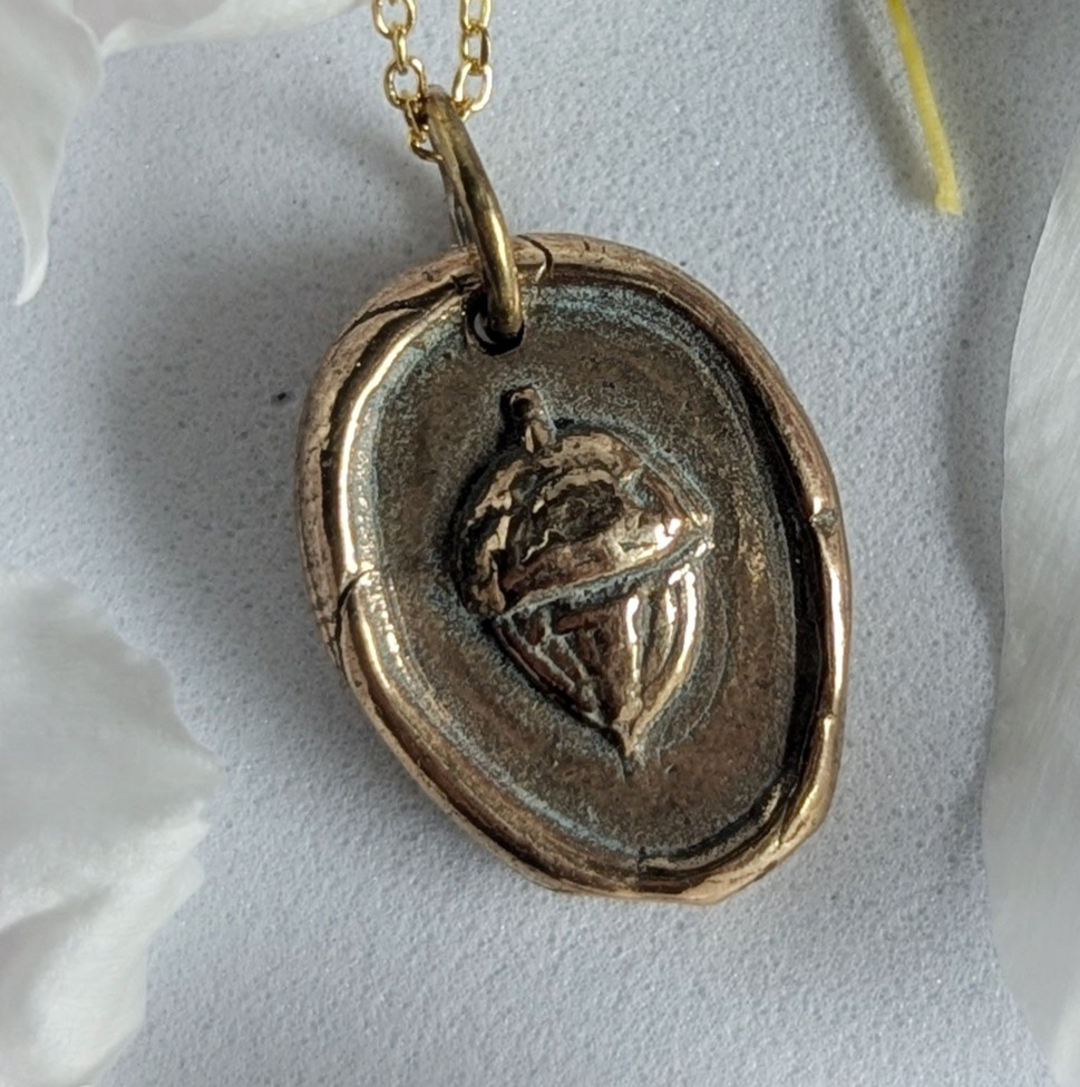 Gold necklace with a pendant on a background of pink flower petals