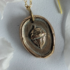 Gold necklace with a pendant on a background of pink flower petals