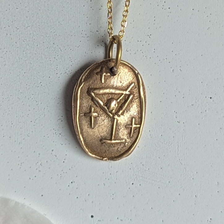 Gold necklace with a pendant on a white background with pink petals