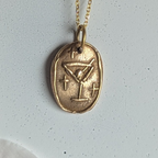 Gold necklace with a pendant on a white background with pink petals